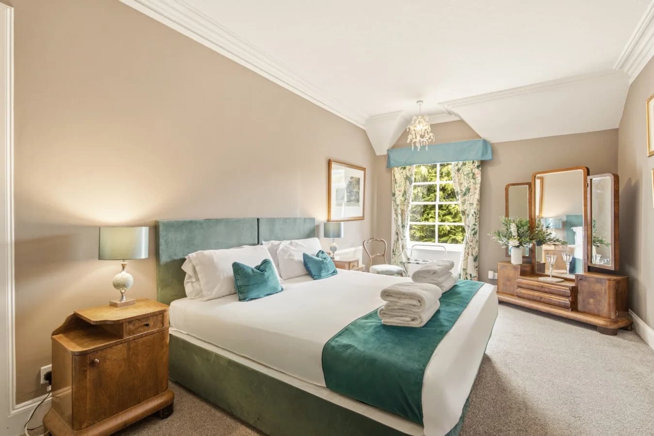 Super king bedroom with teal headboard and vintage dressing table.