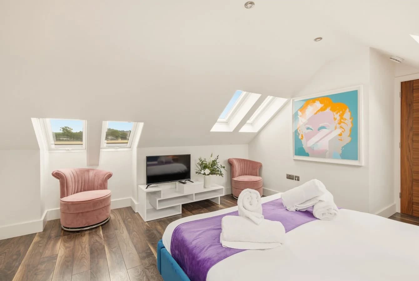 Bedroom with skylights, oak flooring and contemporary artwork