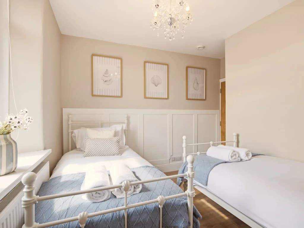 Twin bedroom with wall panelling and framed shell artwork