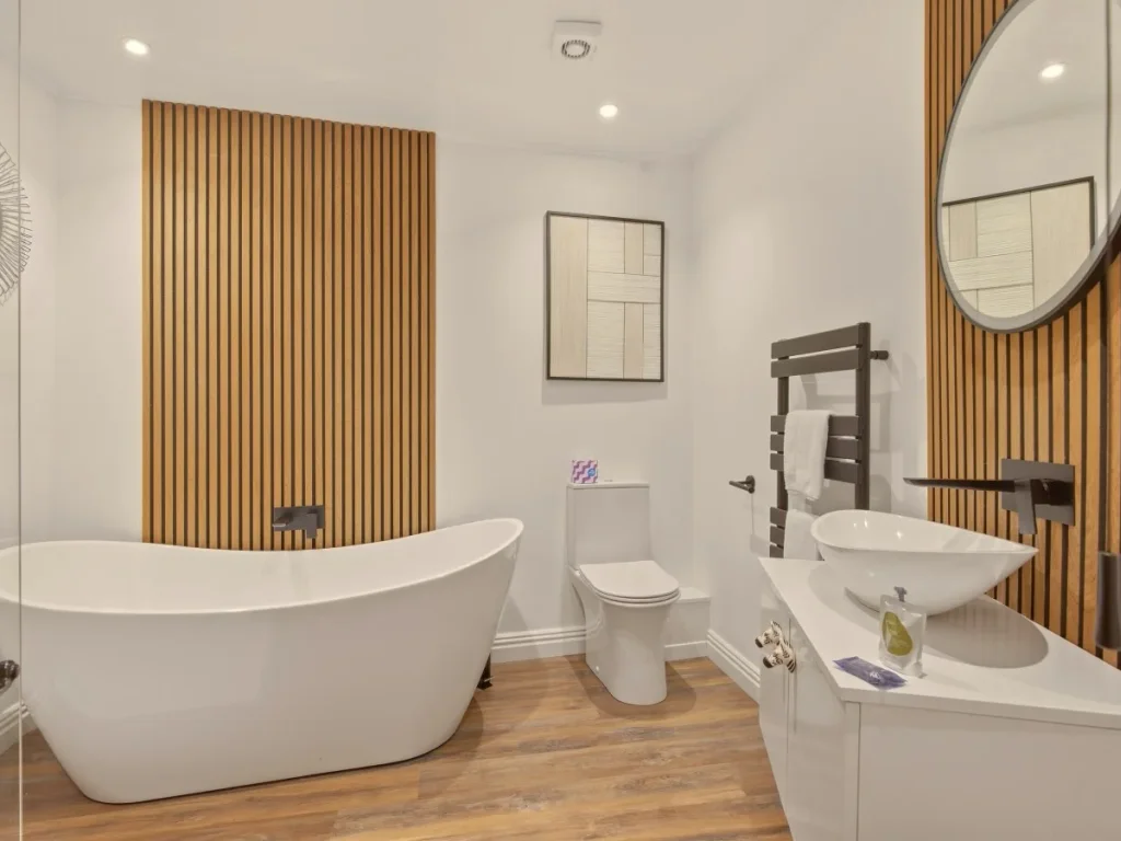 Family bathroom with freestanding bath, wood panelling and modern fittings.