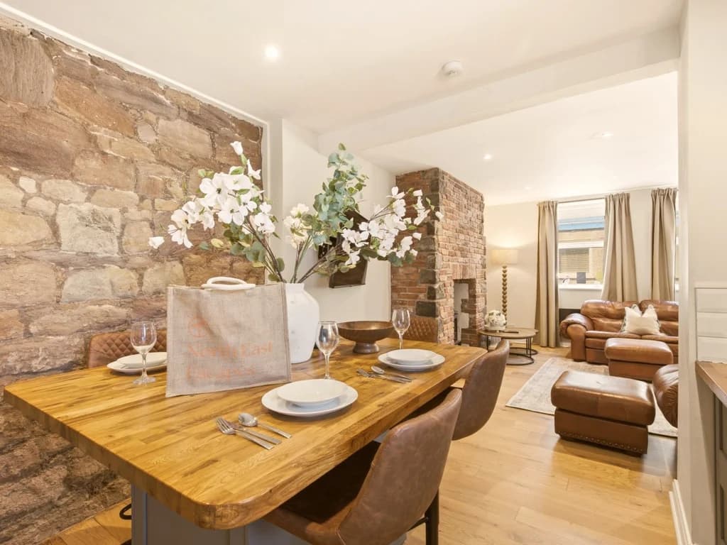 Dining area with stone feature wall and open-plan living beyond.