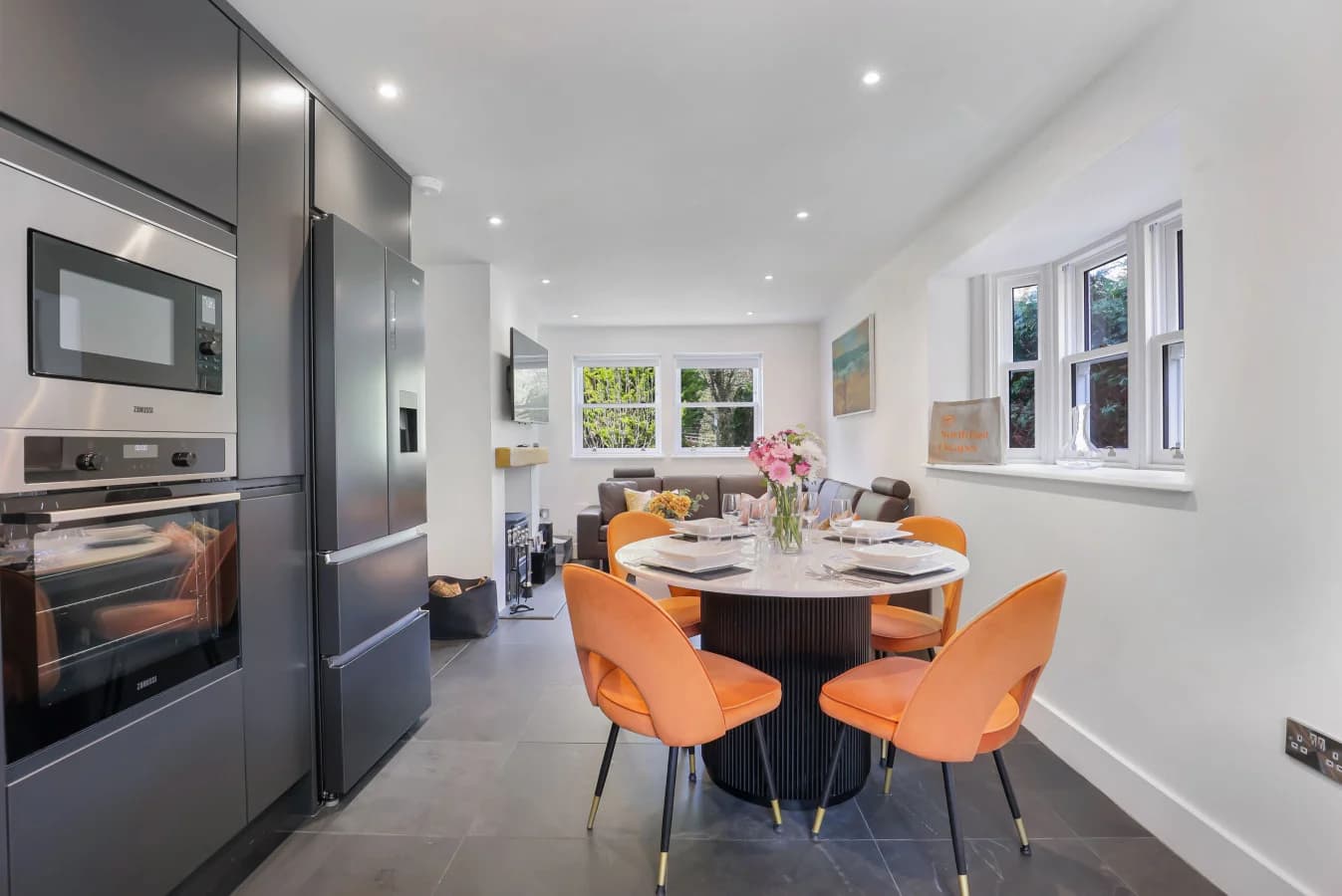Open-plan dining area with orange chairs and quartz table