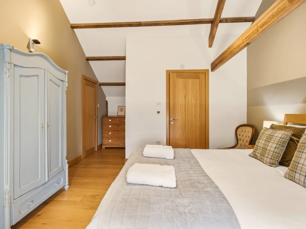 King-size bed with timber beams and freestanding wardrobe