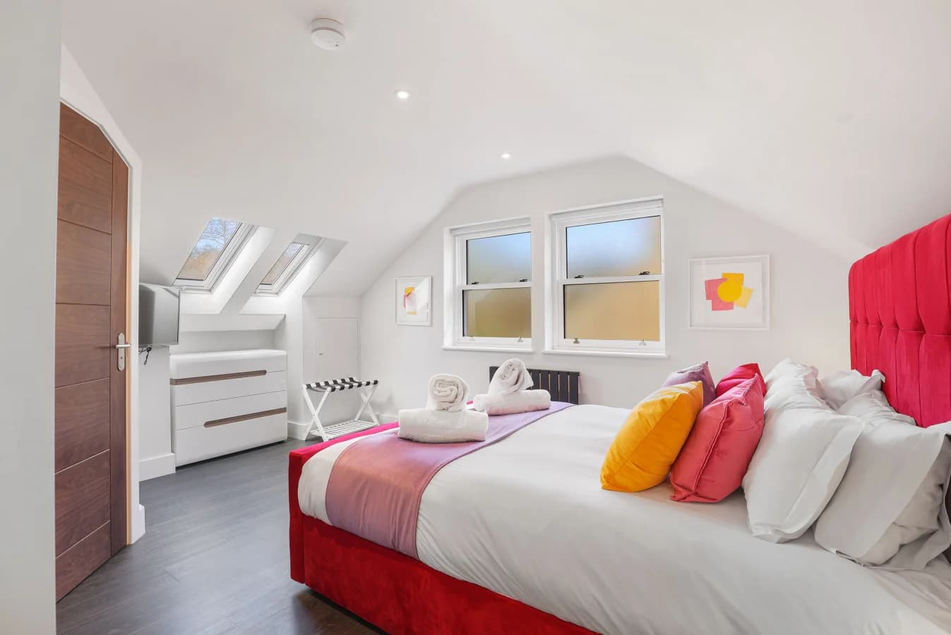 King bedroom with red upholstered headboard and skylights