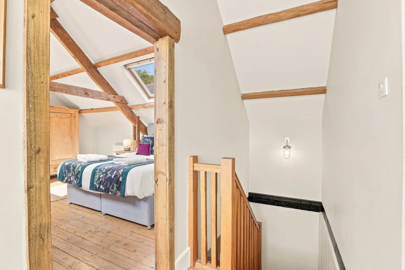 Spacious bedroom with skylight, exposed beams and wooden flooring