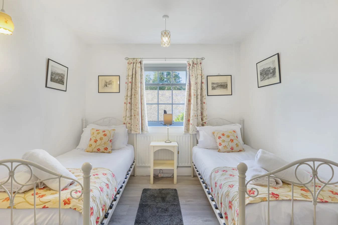 Bright twin bedroom with floral bedding and painted furniture