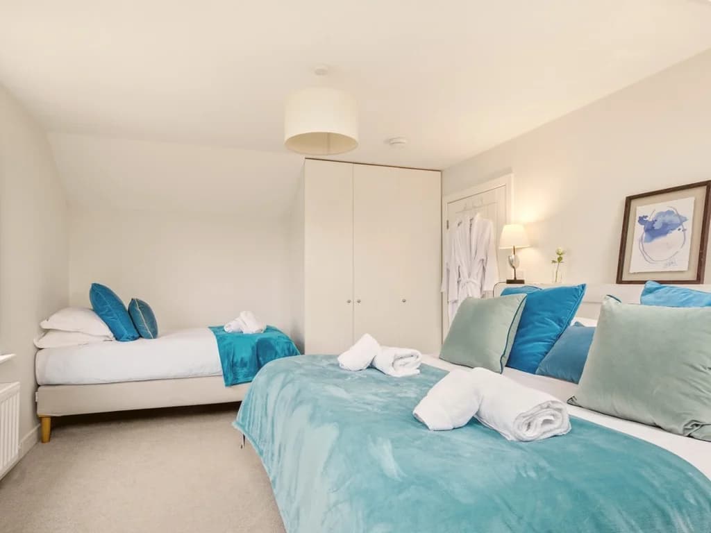 Flexible family bedroom with super king and single bed beneath vaulted ceiling