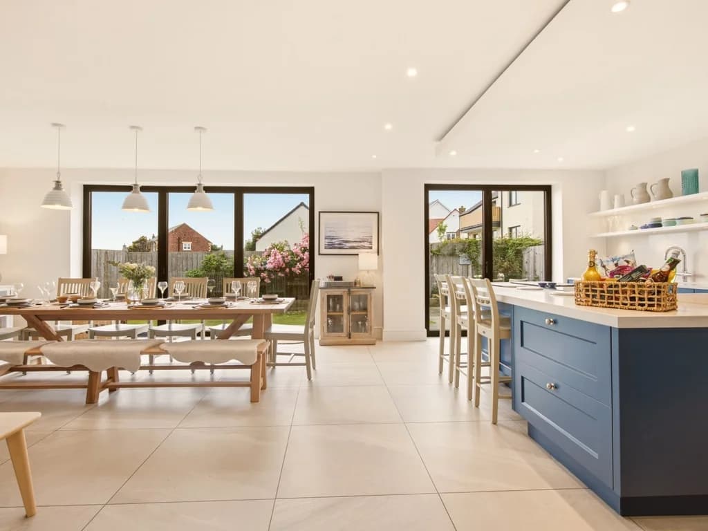 Open-plan kitchen and dining area with blue island and full-width dining table
