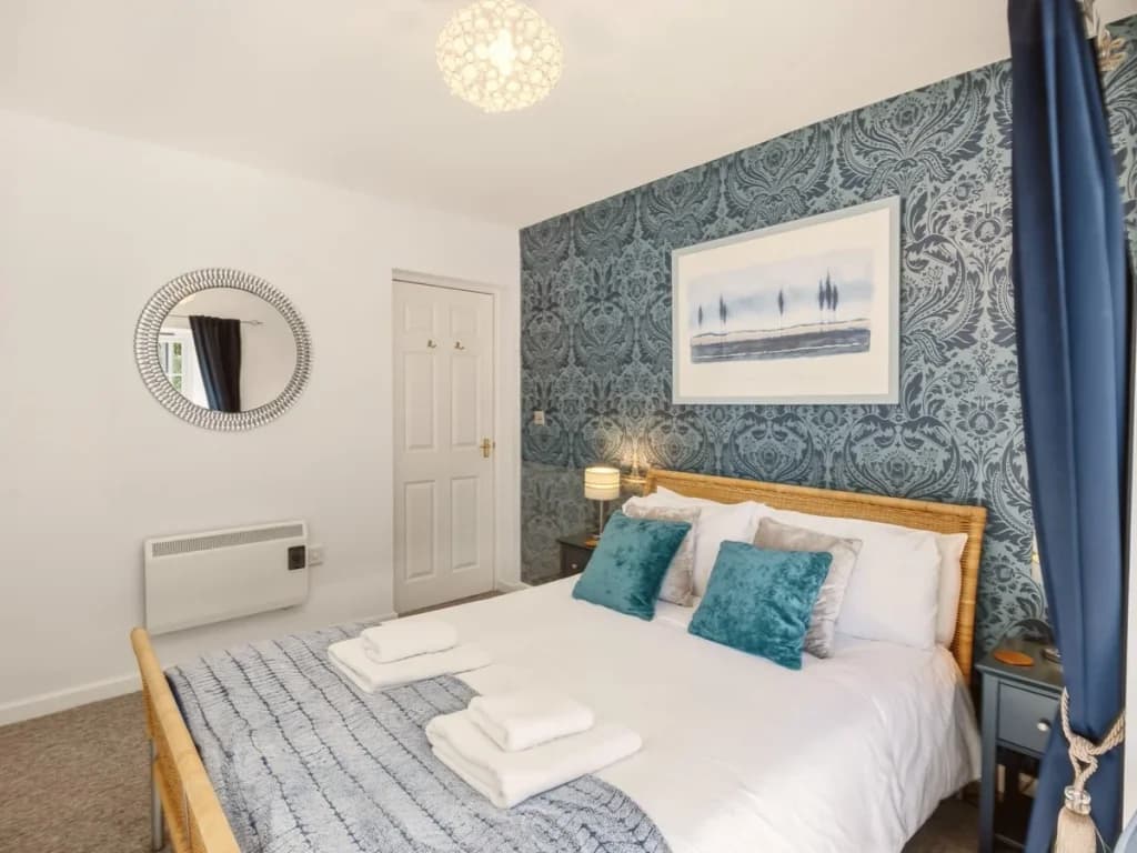 King bedroom with blue feature wall, bedside lighting and large mirror