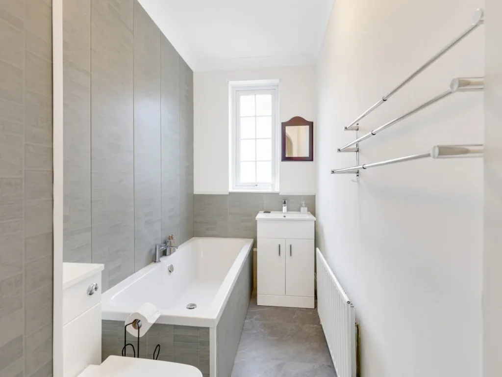 Family bathroom with bath, shower, wash basin and useful storage rails