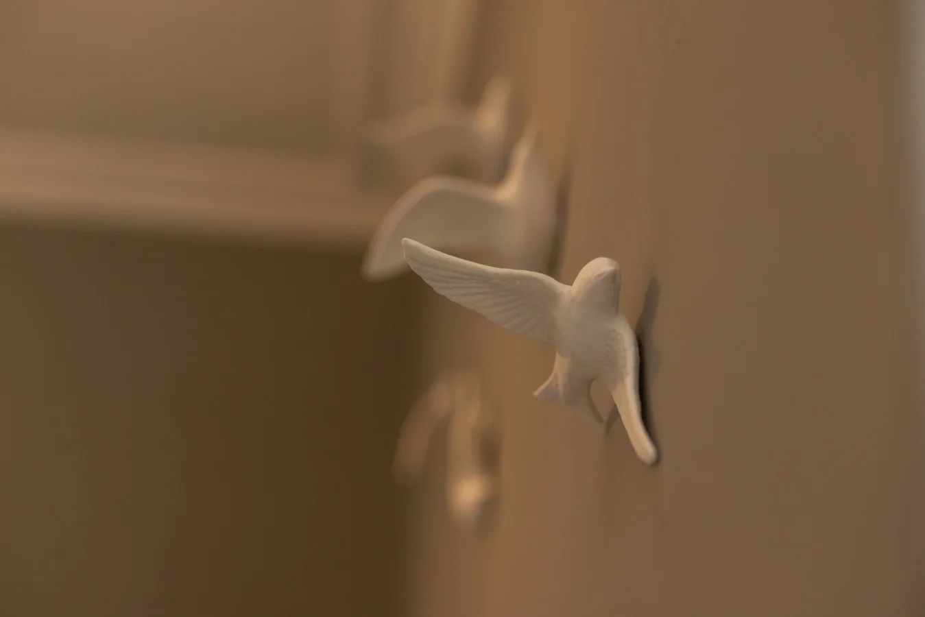 Decorative white bird wall hooks in the bedroom.