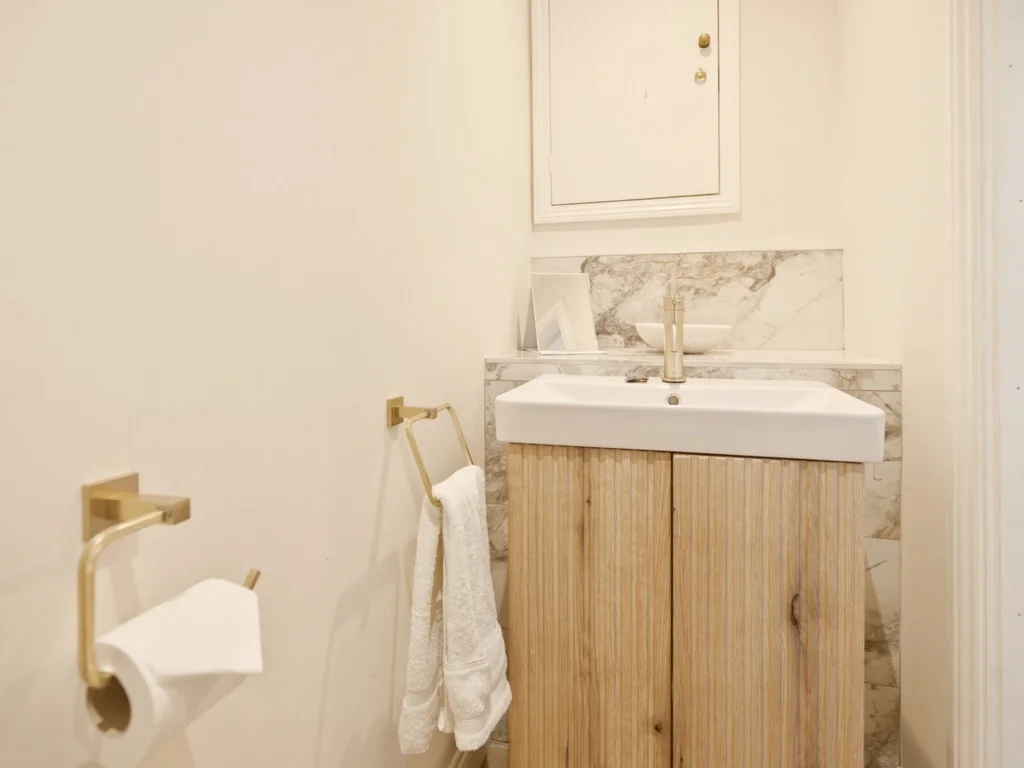 Cloakroom vanity with wood-effect cabinet and marble-effect splashback.