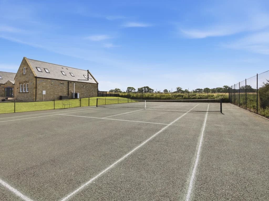 Shared tennis court with full-size net and open countryside setting