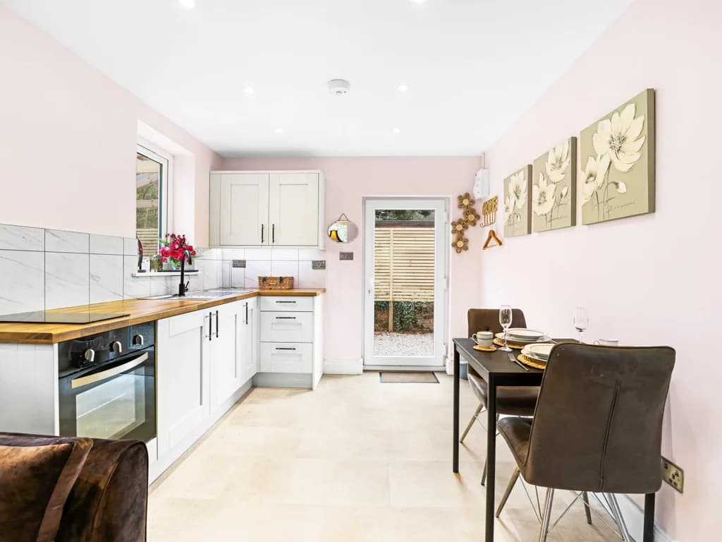 This modern kitchenette features white cabinetry and wood-effect countertops, opening into a dining area.