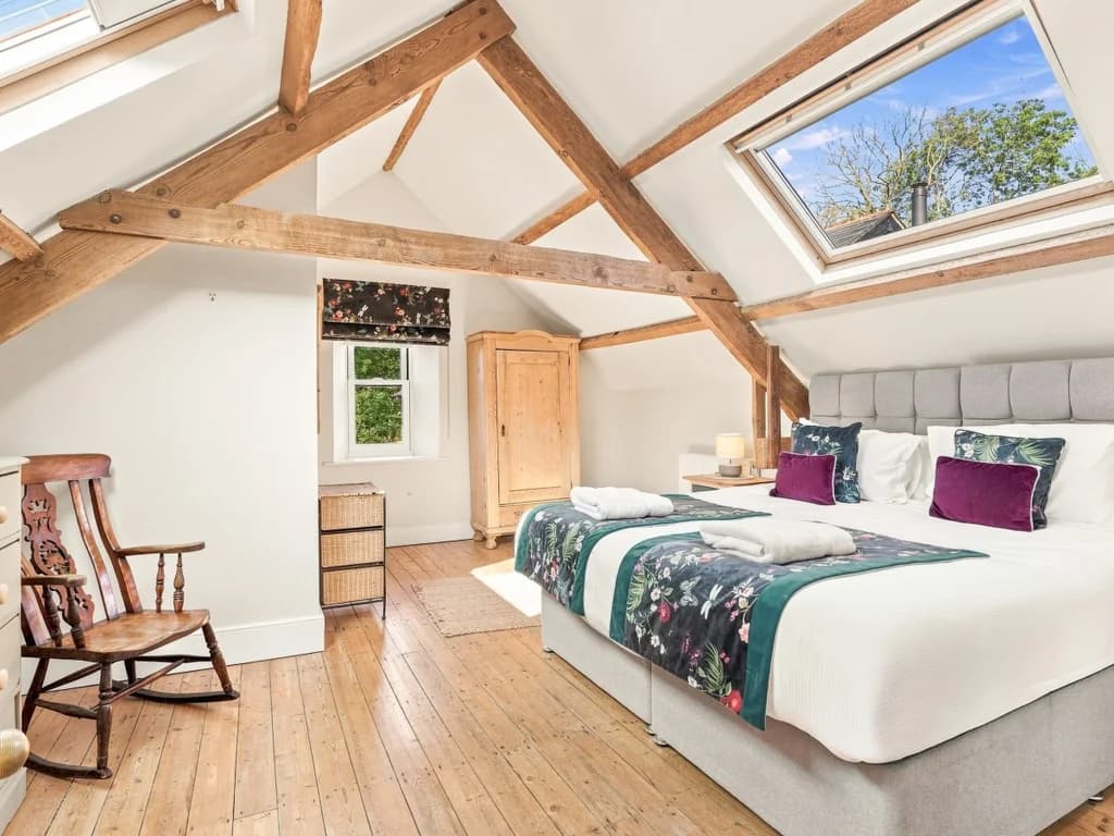 Bright bedroom with exposed beams, skylights and wooden floors