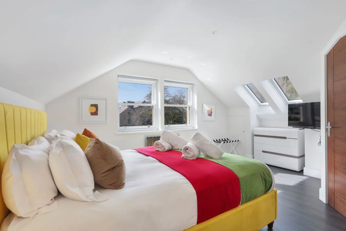 King bedroom with yellow upholstered headboard and skylight