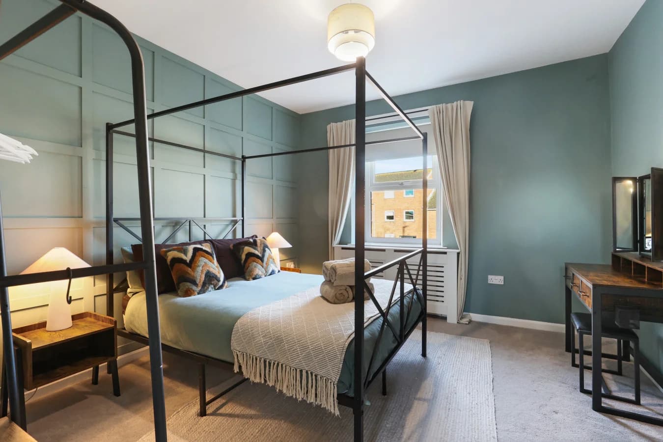 Four-poster bedroom with rich teal panelling and boutique styling