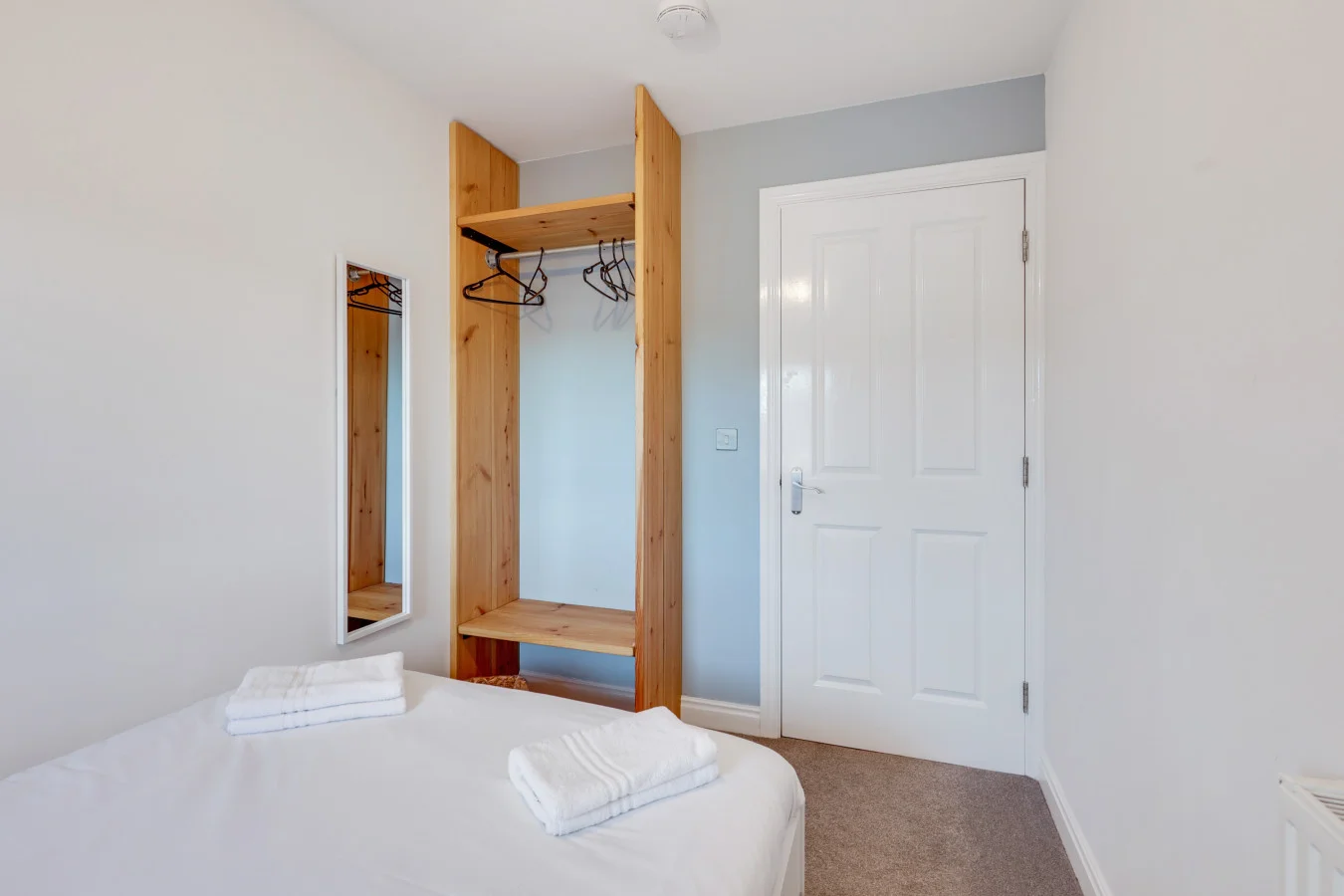 Minimalist bedroom featuring natural wood storage and crisp white décor