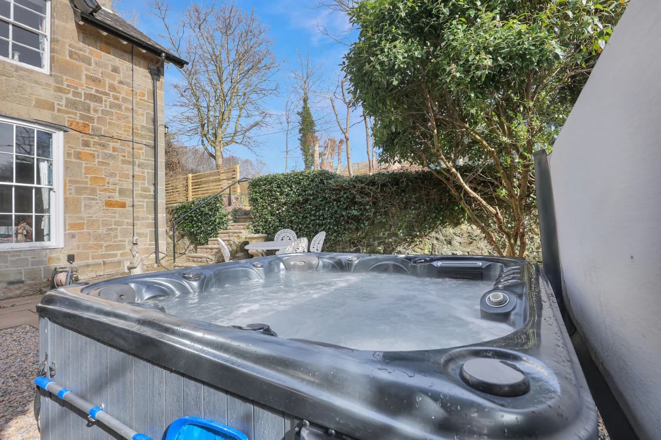 Private hot tub set beside the cottage within mature garden grounds