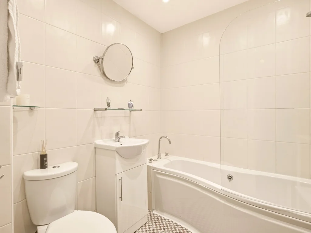 Family bathroom with bath, overhead shower and tiled walls.