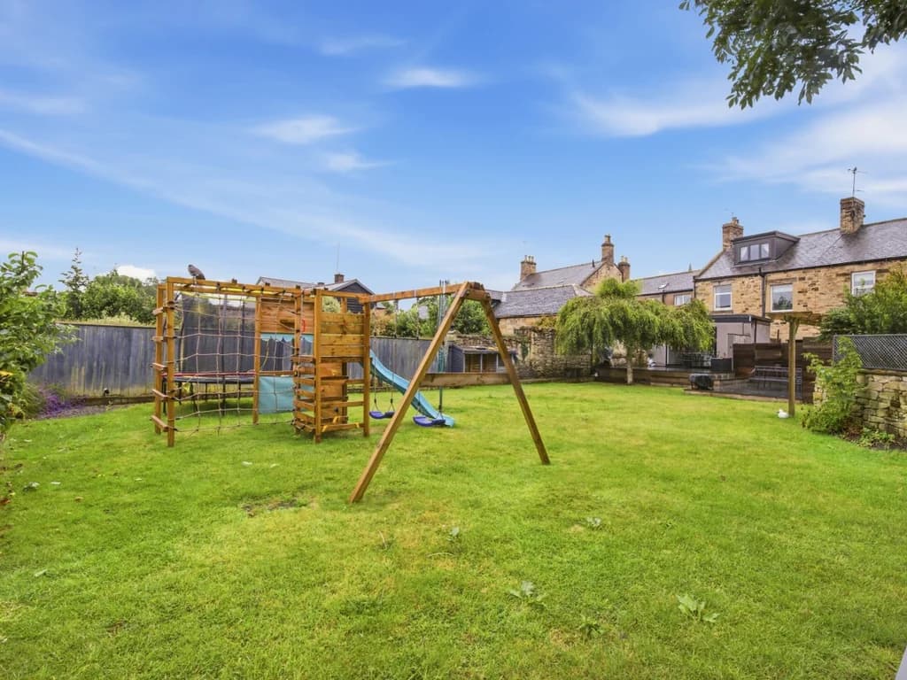 Large enclosed garden with lawn, playset and space for family fun.