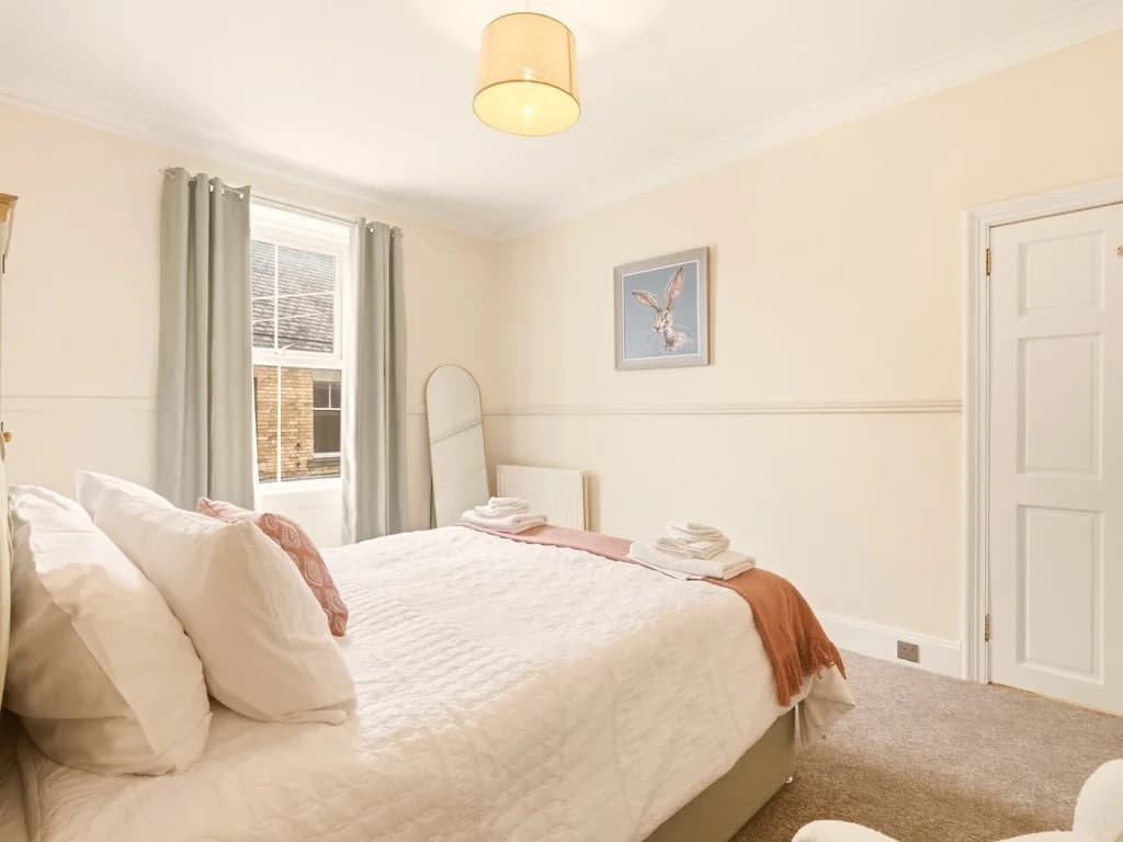 King bedroom with soft neutral décor and large wardrobe.