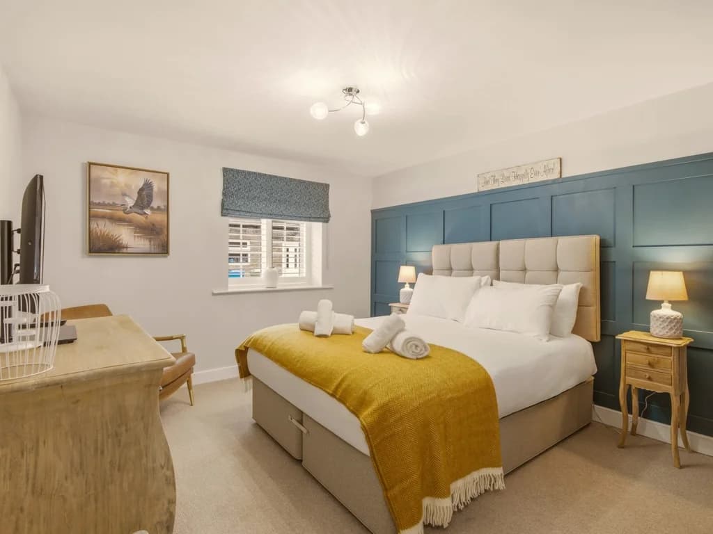 Spacious zip-link king bedroom with feature wall and oak bedside furniture
