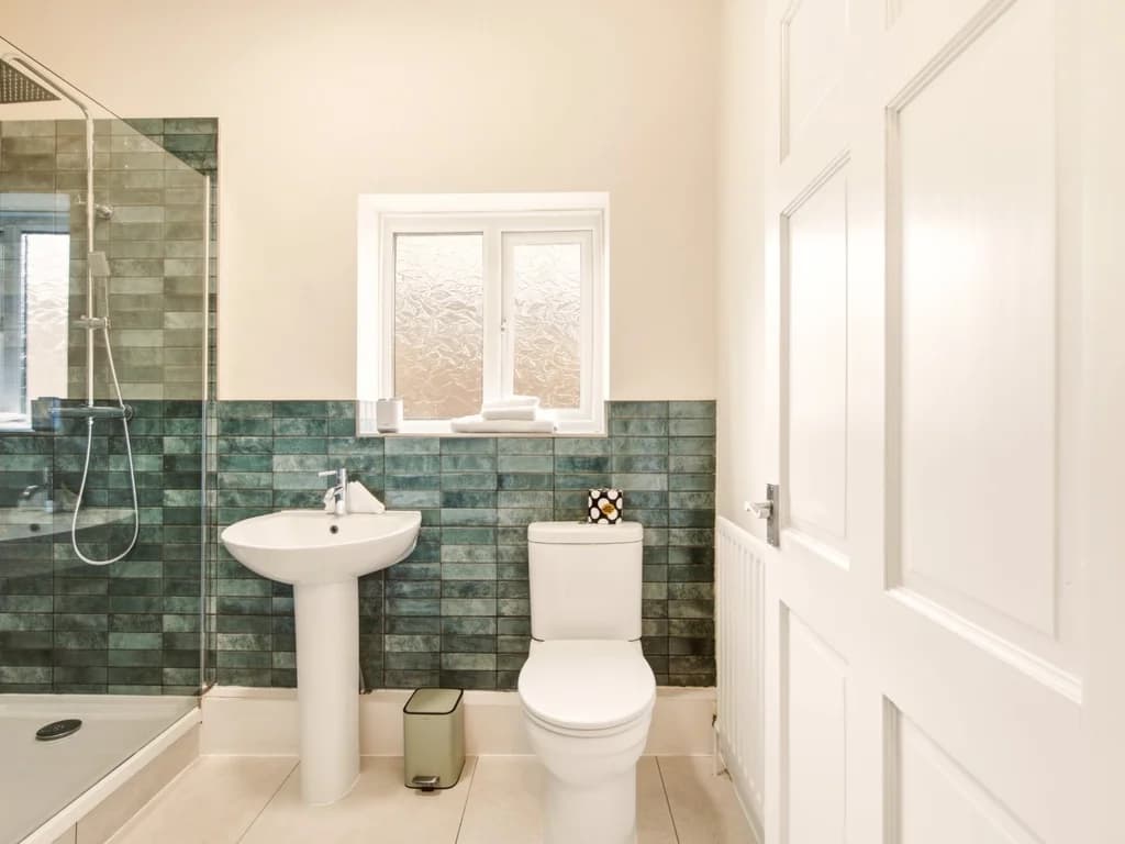 Bathroom with walk-in shower, blue tiled walls and pedestal basin.