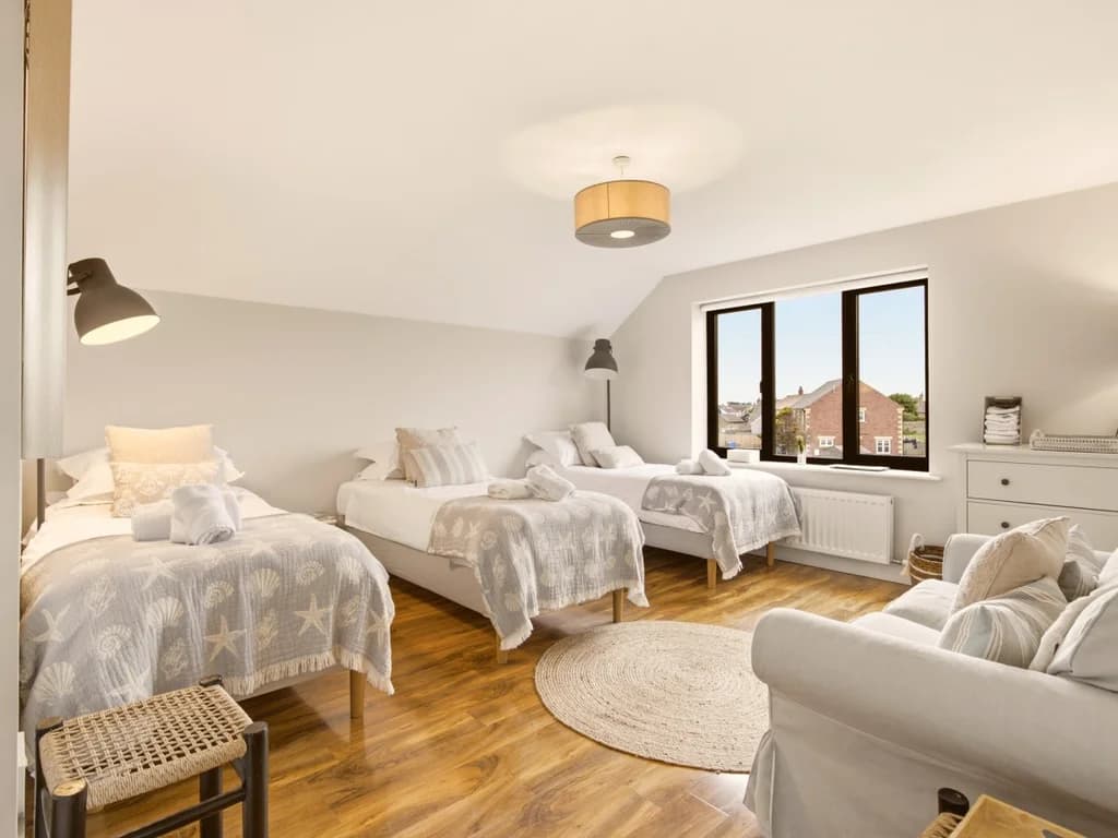 Spacious family bedroom with three single beds and soft neutral décor