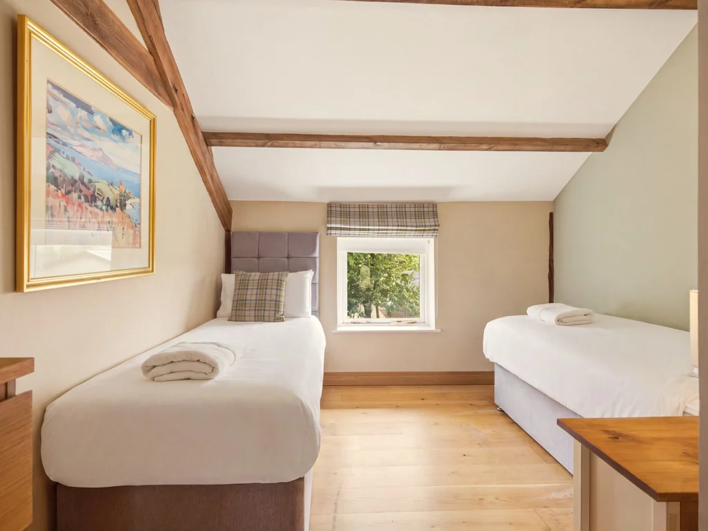 Twin bedroom with two single beds, exposed beams and garden views