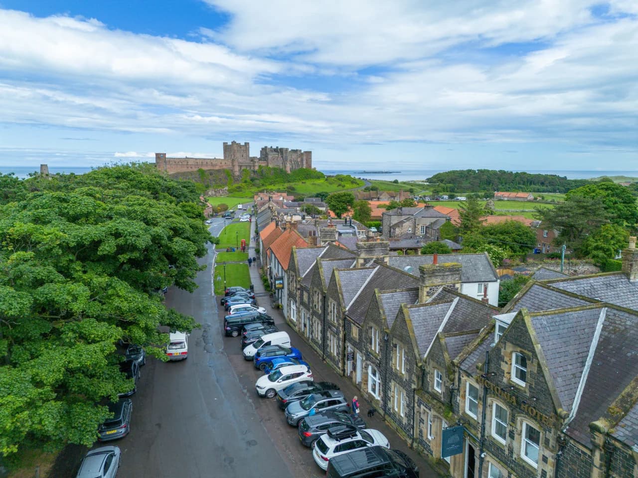 Elevated view of Bamburgh Castle, village rooftops and coastline