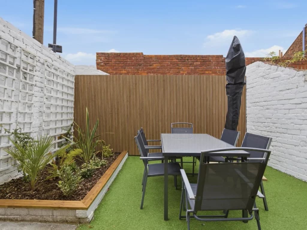 Enclosed outdoor space with dining table, seating and planted borders
