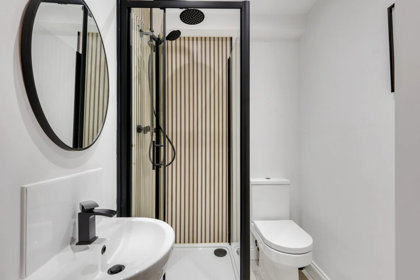 Modern shower room with striped tiling, matte black fittings and round mirror