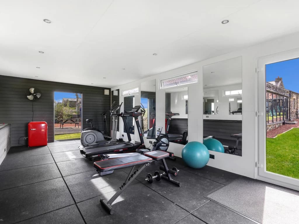 Shared gym with garden views and mirrored wall