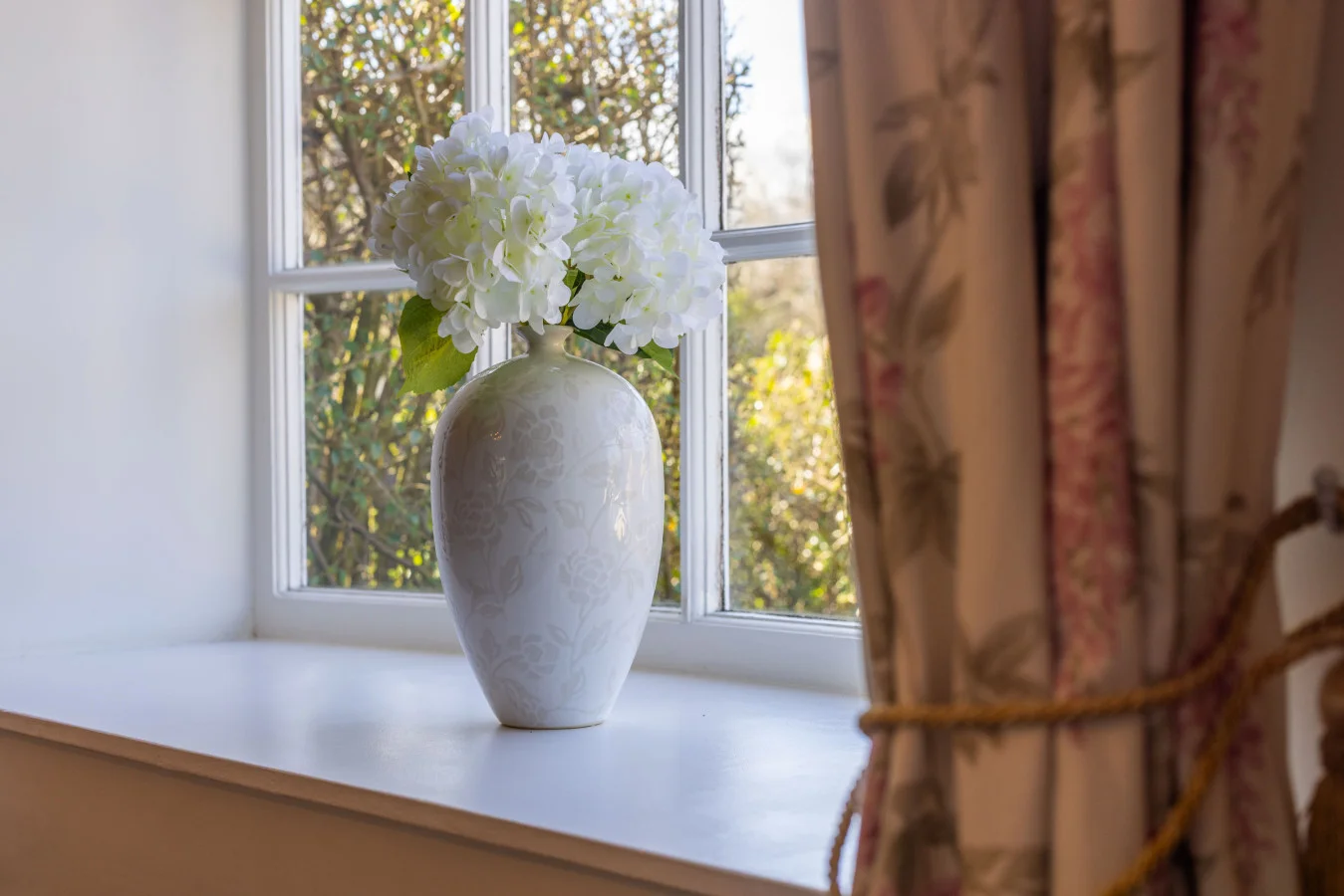 Window-side floral arrangement with garden views