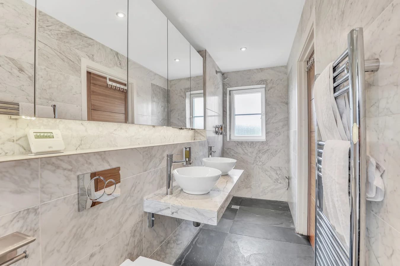 Marble-clad ensuite with floating vanity and large mirror