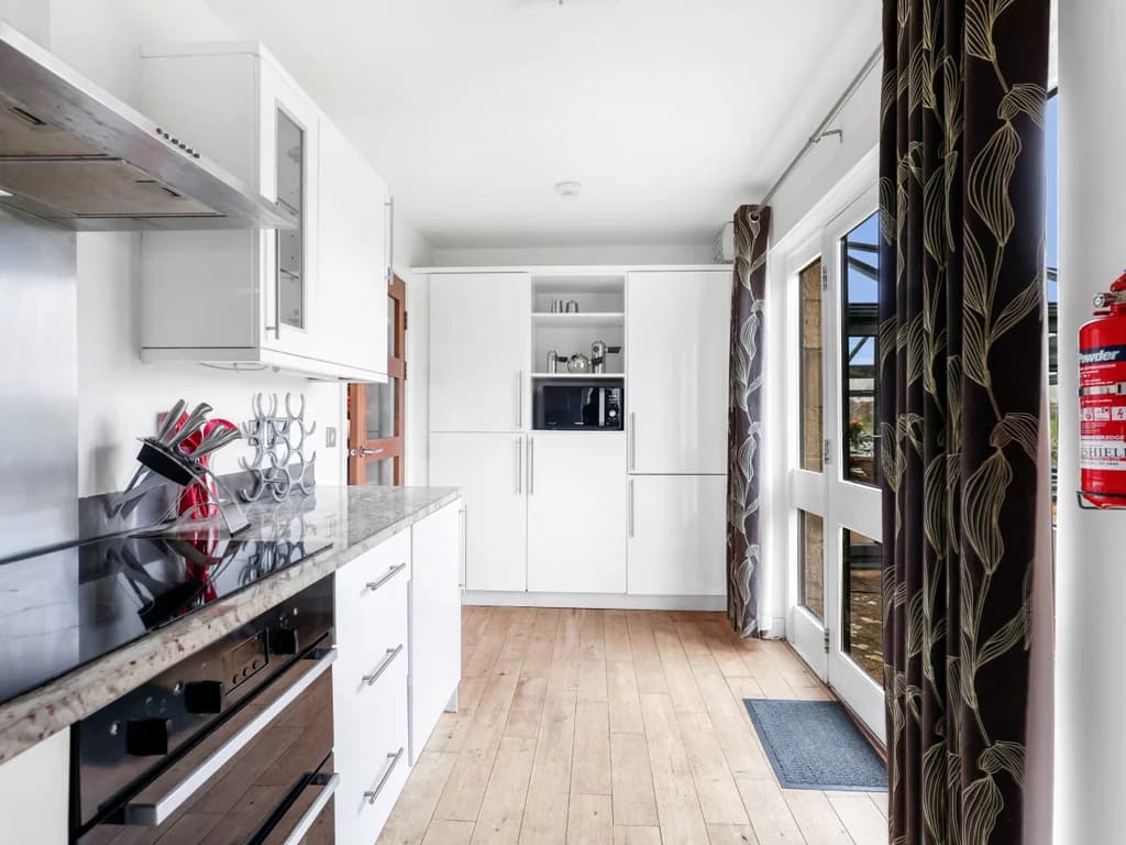 Galley-style kitchen with integrated appliances and timber flooring