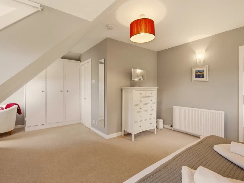 Spacious king bedroom with oak furniture and soft lavender-toned décor