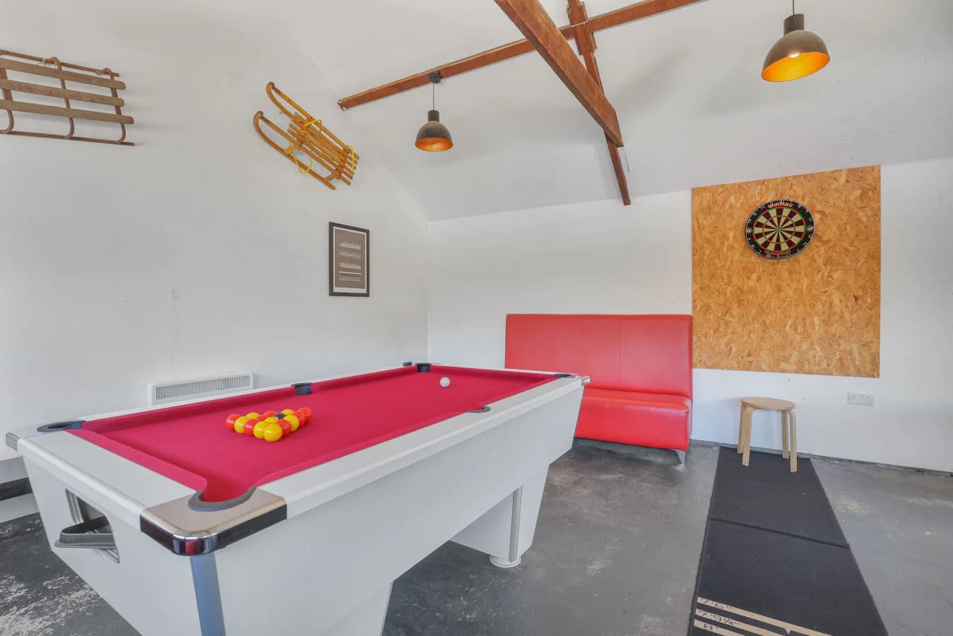 Shared games room with pool table, dartboard and red bench seating