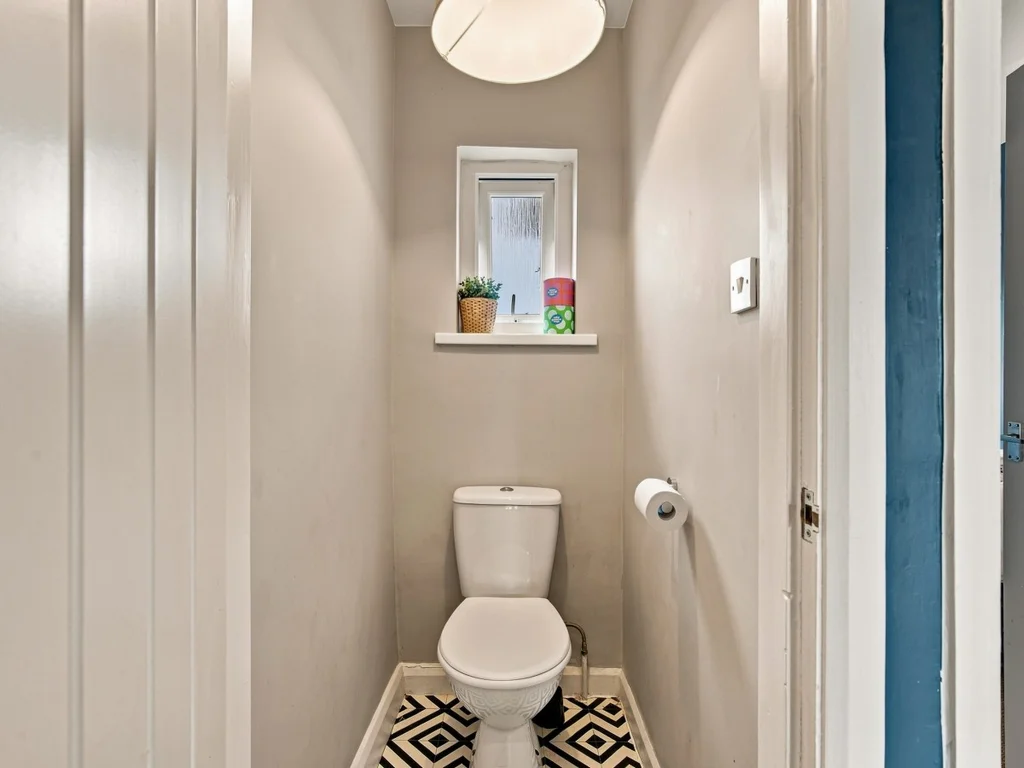 Separate WC with toilet, wash basin and patterned tile flooring.