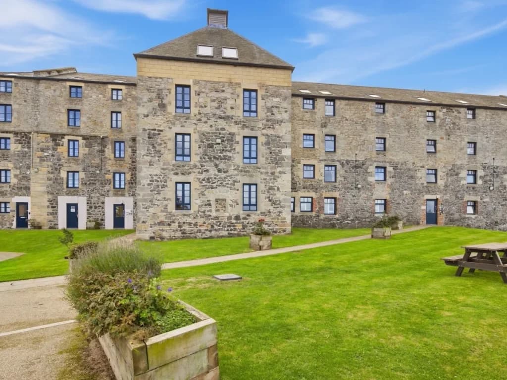 Waren Mill exterior with shared lawn, picnic seating and stone façade
