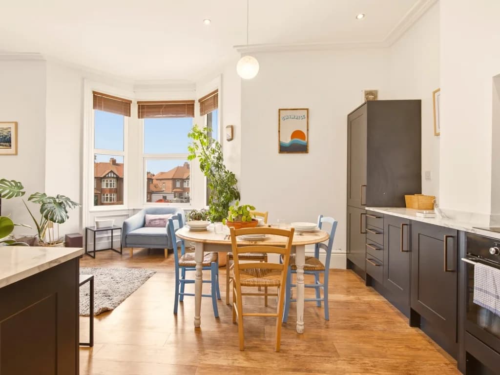 Open-plan kitchen, dining and living space with bay window outlook.