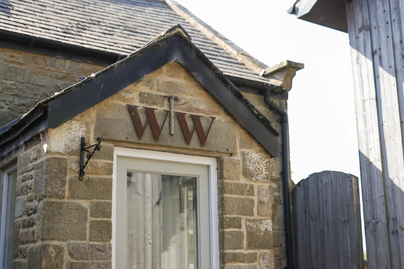 Stone entrance detail with Woodworkers Cottage initials above the door