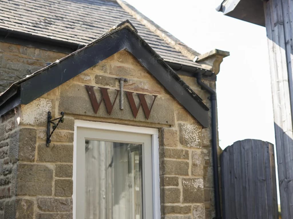 Stone entrance detail with Woodworkers Cottage initials above the door