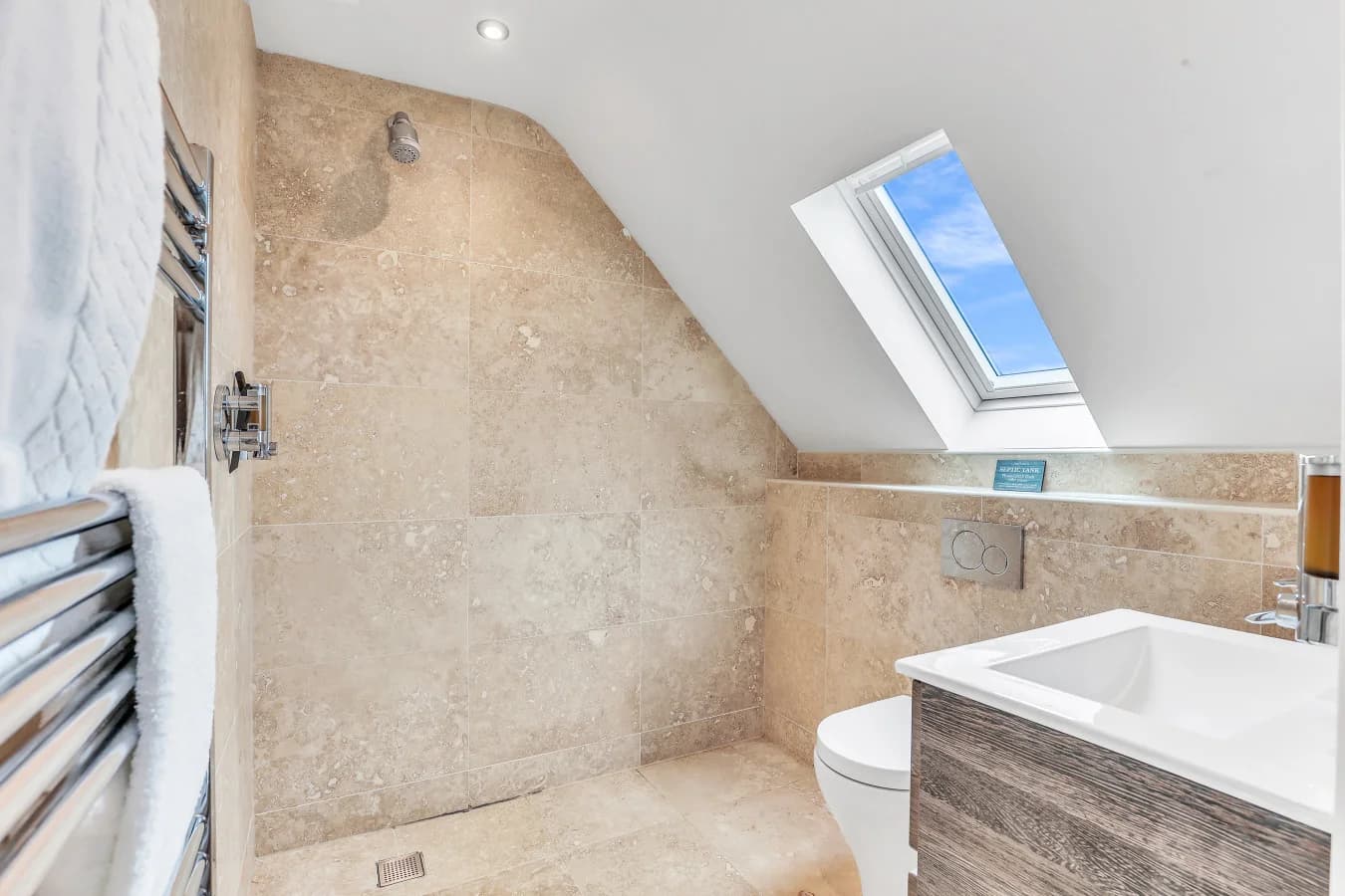 Ensuite bathroom with bath, skylight and stone-effect tiling