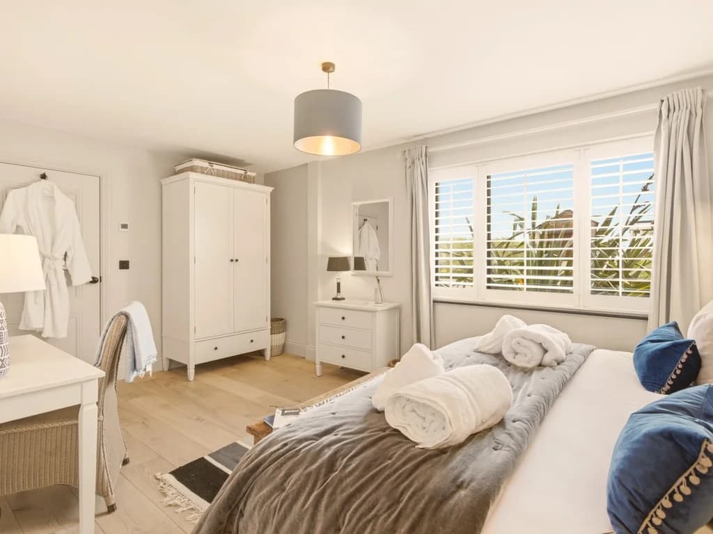 Spacious super king bedroom with plantation shutters and painted wardrobe