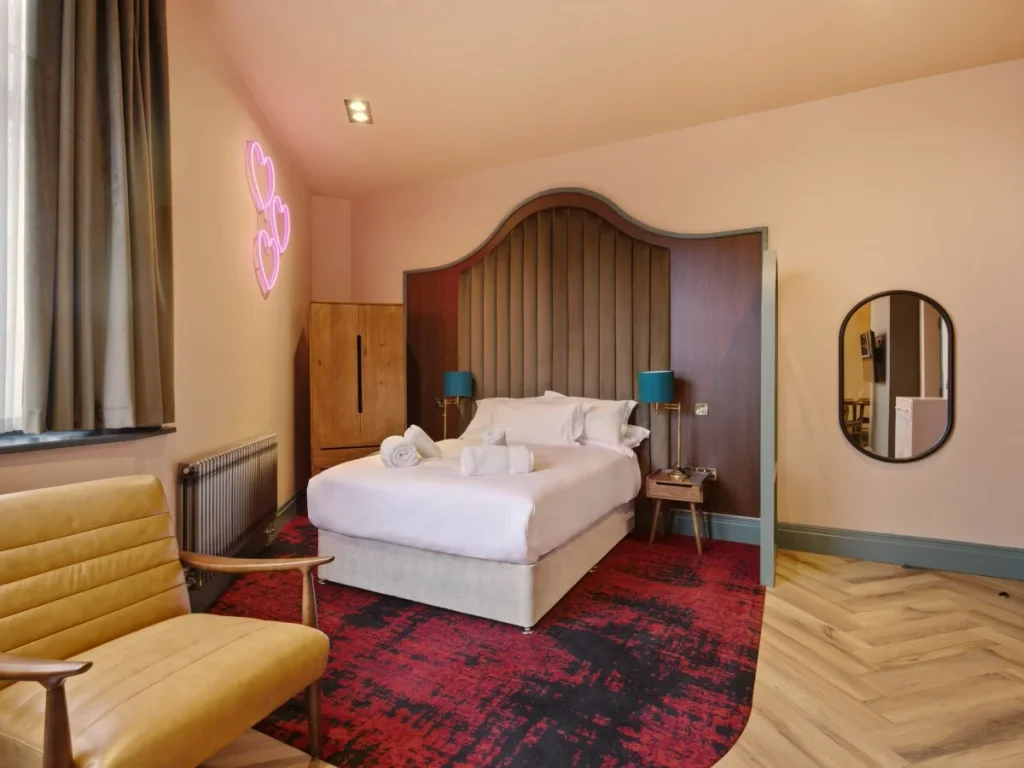Open-plan studio with double bed, seating and distinctive neon wall light.