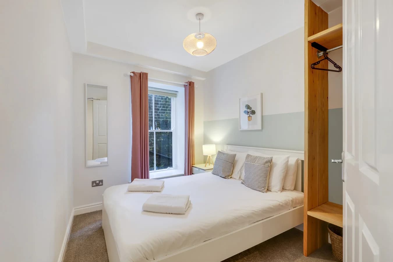 Double bedroom with soft pastel accents, natural wood storage and garden views