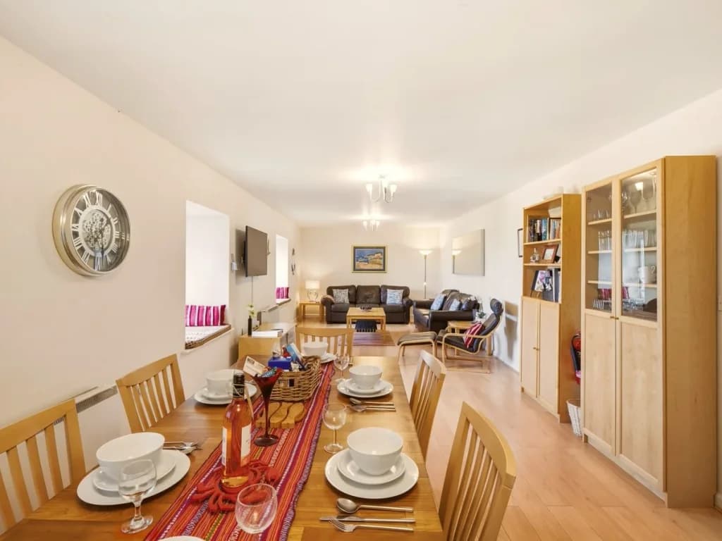 Open-plan dining and living space with wooden flooring and ample seating
