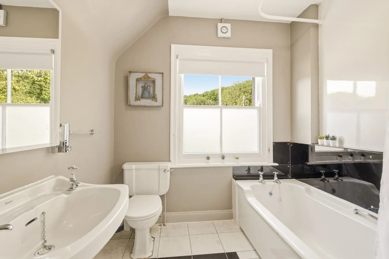 Bright bathroom with bath, pedestal basin and heated towel rail